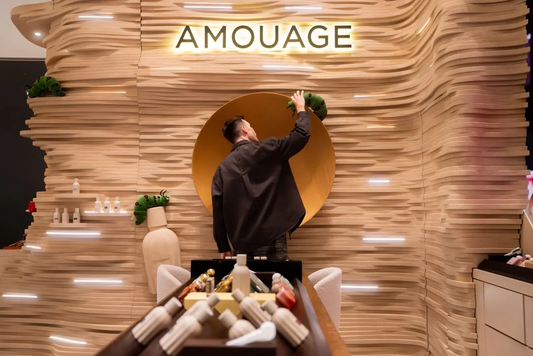 An artisan arranging an Amouage boutique display