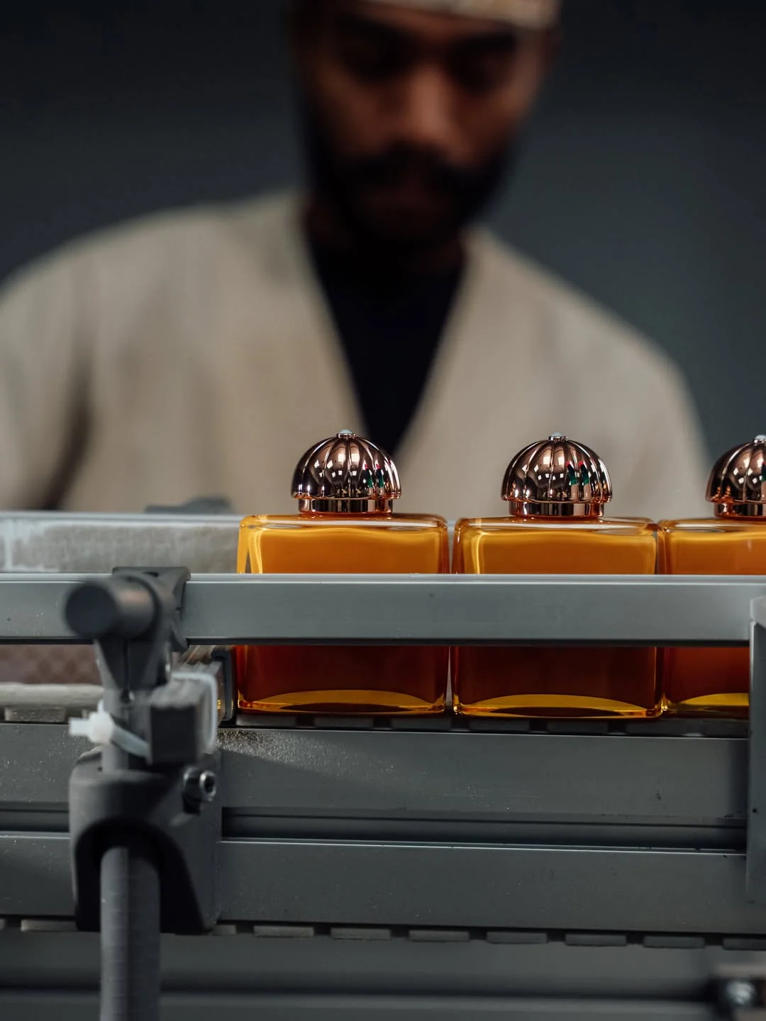 A craftsman working with Amouage perfume bottles on the production line