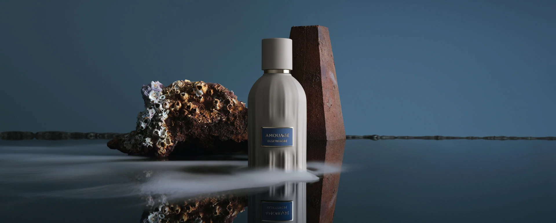Amouage perfume beside Omani rocks, reflected in water